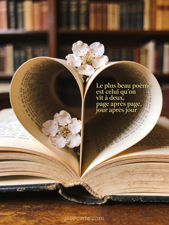 Livre ancien ouvert avec pages formant un cœur et fleurs de cerisier pressées et le texte Le plus beau poème