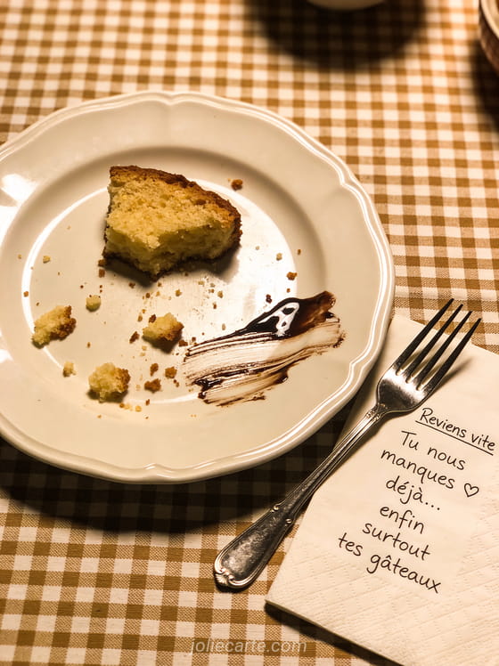 Assiette vide avec miettes de gâteau fourchette et petit mot reviens vite sur une nappe à carreaux