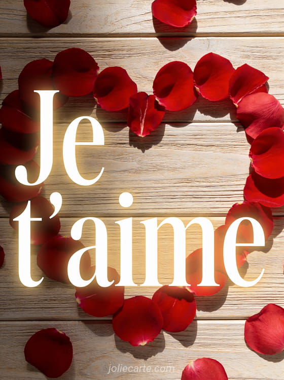 Cœur formé par des pétales de rose rouge posés sur un fond de bois clair avec le texte Je t'aime