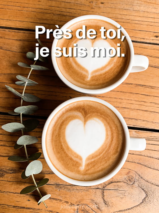 Deux tasses de café vues du dessus avec mousse en cœur sur table en bois rustique avec eucalyptus
