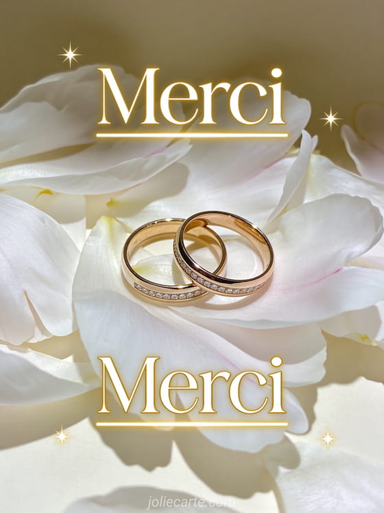 Deux alliances sur lit de pétales de pivoine blanche avec étoiles scintillantes et le texte Merci en lettres dorées Art Déco