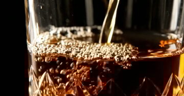 Postal virtual animado com uma sequência de imagens: um whiskey dourado é derramado em um copo de cristal sobre um fundo preto, com a mensagem de feliz aniversário.