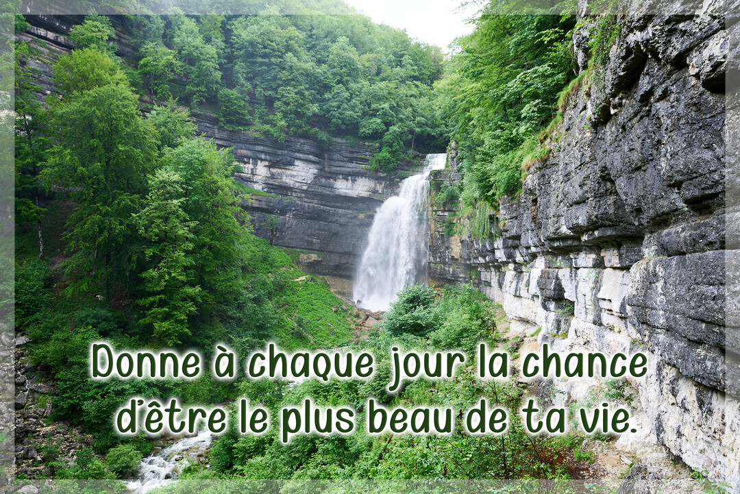 Une majestueuse cascade se jette d'une falaise rocheuse au cœur d'une forêt dense et verdoyante, sous une lumière douce et naturelle.