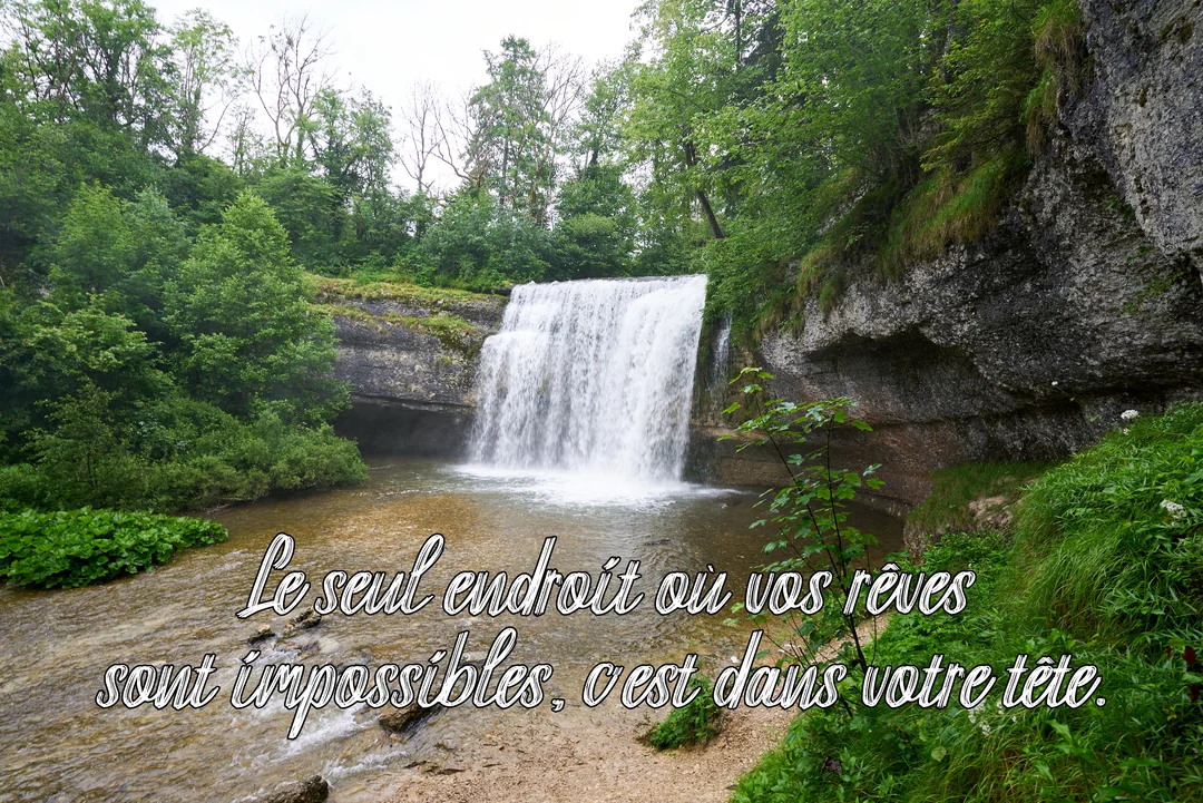Une majestueuse cascade se déverse dans une rivière au cœur d'une forêt luxuriante, avec une citation inspirante superposée sur l'eau.