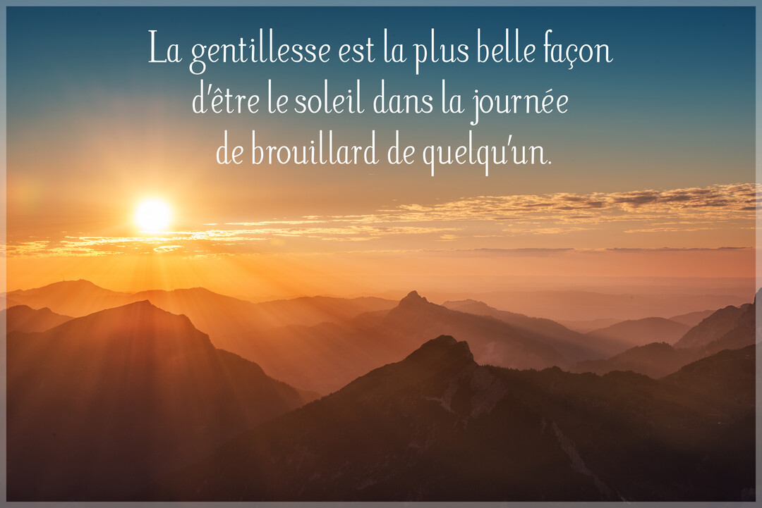 Un soleil éclatant se lève sur des chaînes de montagnes, ses rayons dorés perçant une brume matinale, avec une citation sur la gentillesse.