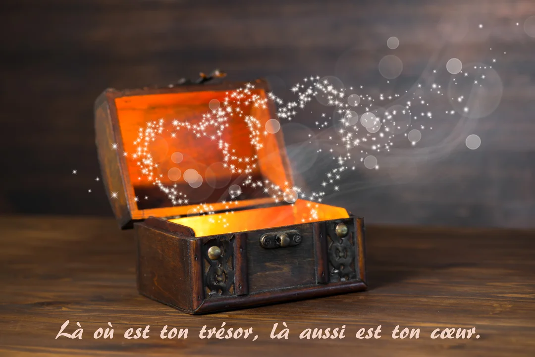 Un coffre en bois rustique est ouvert sur une table, révélant une lueur orangée et une volute d'étoiles scintillantes formant un cœur magique.