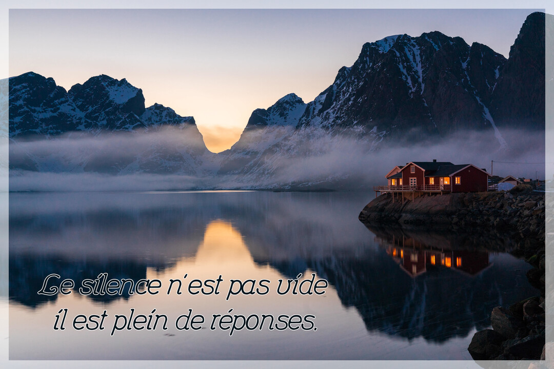 Une maison rouge illuminée se dresse au bord d'un lac calme, reflétant des montagnes enneigées sous un ciel de crépuscule brumeux.