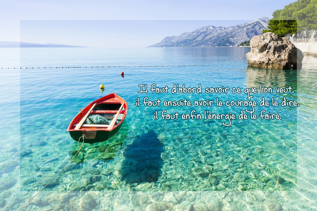 Une petite barque rouge flotte sur une eau cristalline près d'une côte montagneuse ensoleillée, illustrant une citation sur la volonté et l'action.