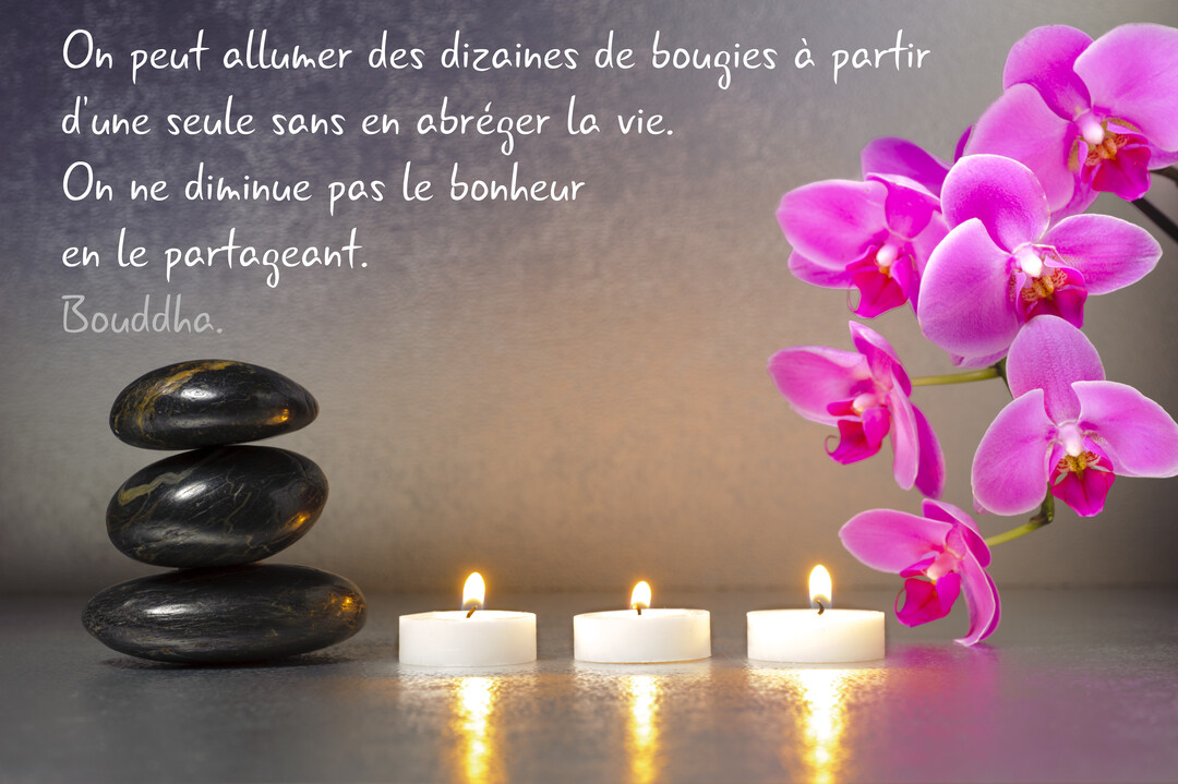 Une composition zen avec des galets noirs empilés, trois bougies allumées et une branche d'orchidées roses sur un fond gris texturé.