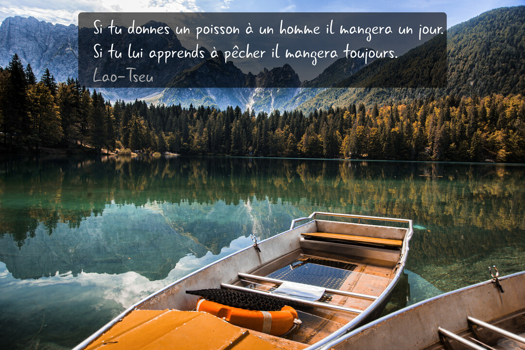 Deux barques à rames amarrées sur un lac de montagne cristallin, reflétant des sapins et des sommets sous un ciel nuageux.