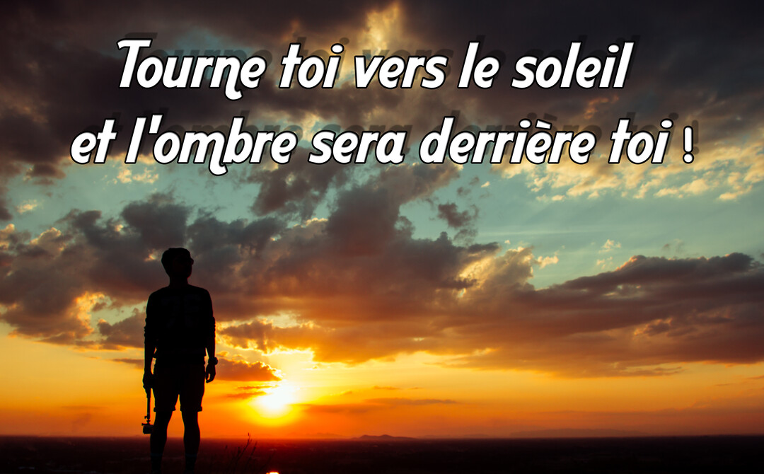 Une silhouette humaine se tient face à un ciel spectaculaire au coucher du soleil, avec des nuages aux teintes orangées et dorées.