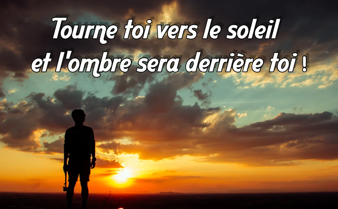 Une silhouette humaine se tient face à un ciel spectaculaire au coucher du soleil, avec des nuages aux teintes orangées et dorées.