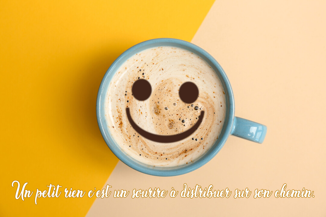 Vue de dessus d'une tasse de café bleue sur fond jaune et beige, avec un smiley dessiné dans la mousse de la boisson.