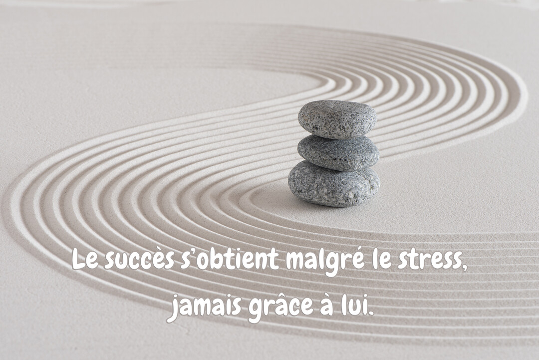 Trois galets gris sont empilés en équilibre sur du sable beige finement ratissé en courbes harmonieuses, évoquant un jardin zen apaisant.