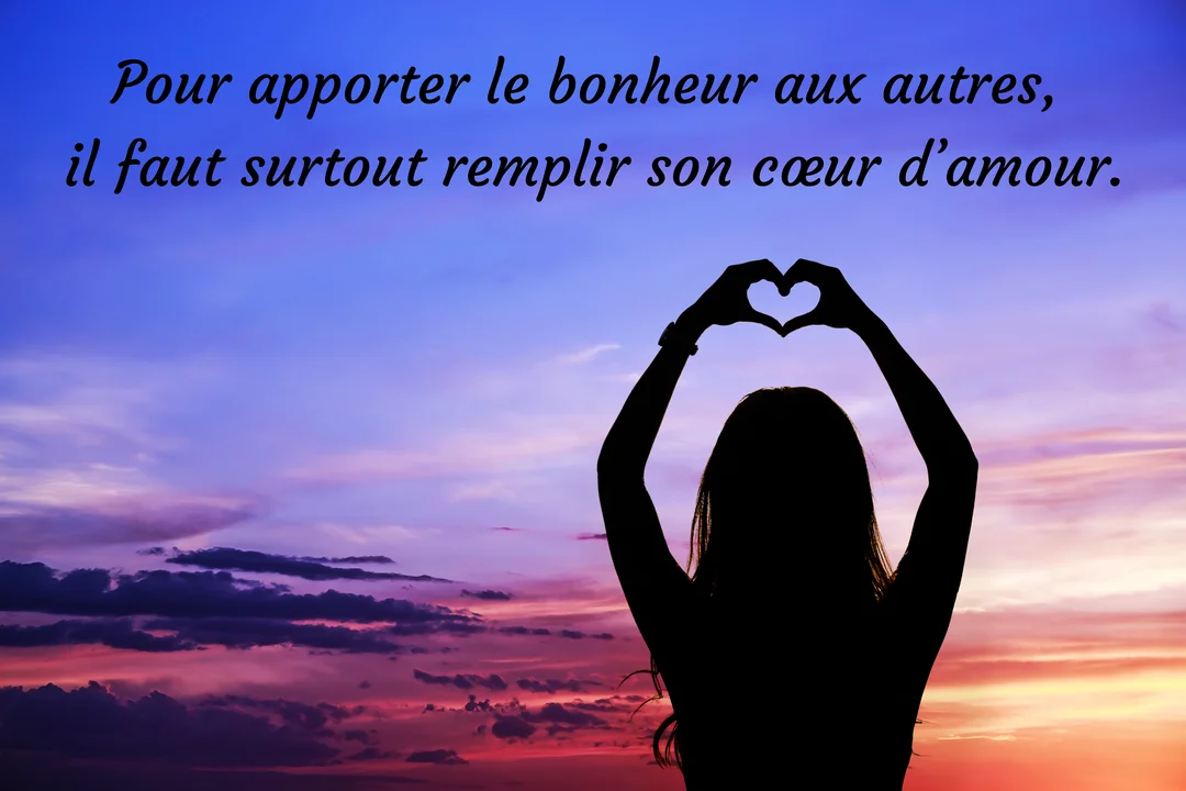 Vue de dos, la silhouette d'une femme forme un cœur avec ses mains au-dessus de sa tête devant un ciel crépusculaire violet et rose.