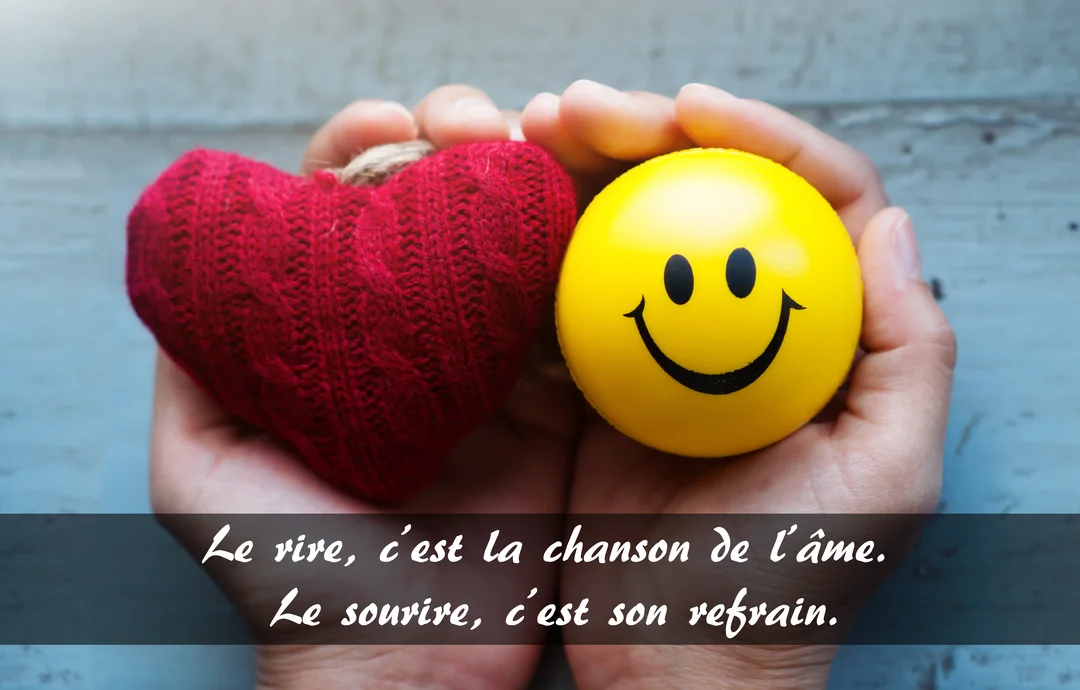 Vue de dessus de deux mains formant un creux, tenant délicatement un cœur rouge tricoté et une balle jaune ornée d'un grand sourire.