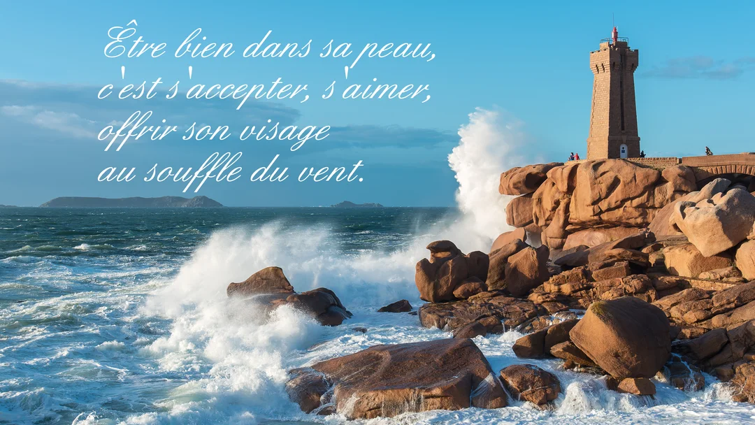 Un phare en granit rose surplombe une mer agitée dont les vagues puissantes s'écrasent sur les rochers sous un ciel bleu dégagé.