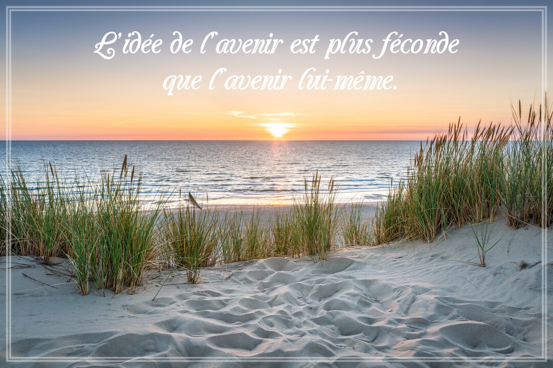 Un paysage de bord de mer au crépuscule, avec le soleil à l'horizon, des dunes de sable et des herbes au premier plan.