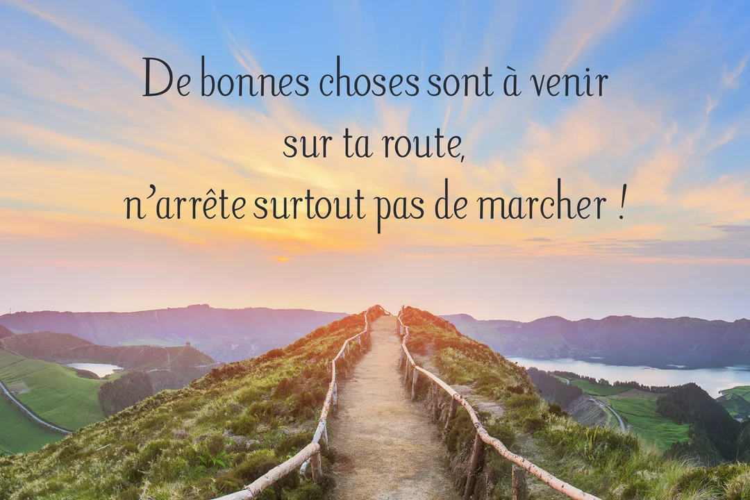 Un sentier de randonnée longe une crête montagneuse verdoyante face à un ciel de coucher de soleil, avec des lacs dans les vallées.