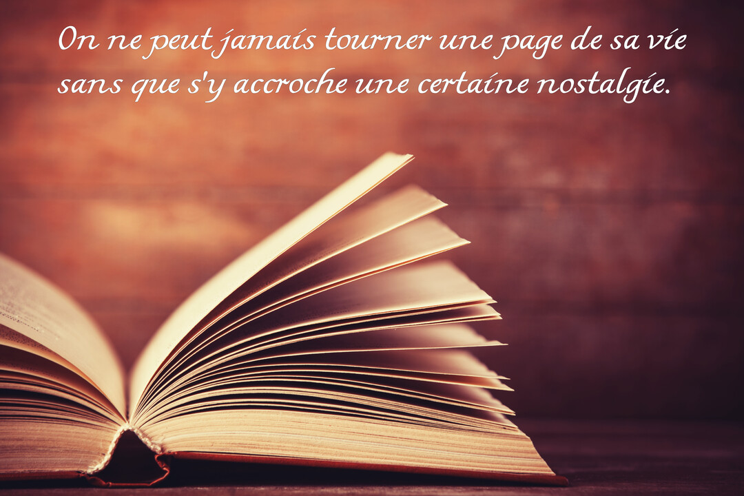 Gros plan sur les pages d'un vieux livre ouvert, sur un fond en bois, avec une citation sur la nostalgie et la vie.