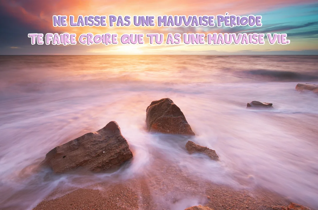 Une photographie en pose longue d'un coucher de soleil sur l'océan, avec des vagues laiteuses couleur pastel entourant des rochers au premier plan.