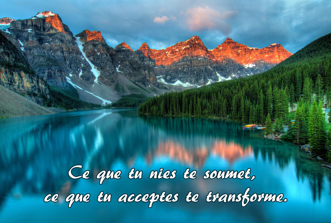 Un lac de montagne serein reflète des sommets enneigés et dorés par le soleil, avec une forêt de sapins verts sur la rive.