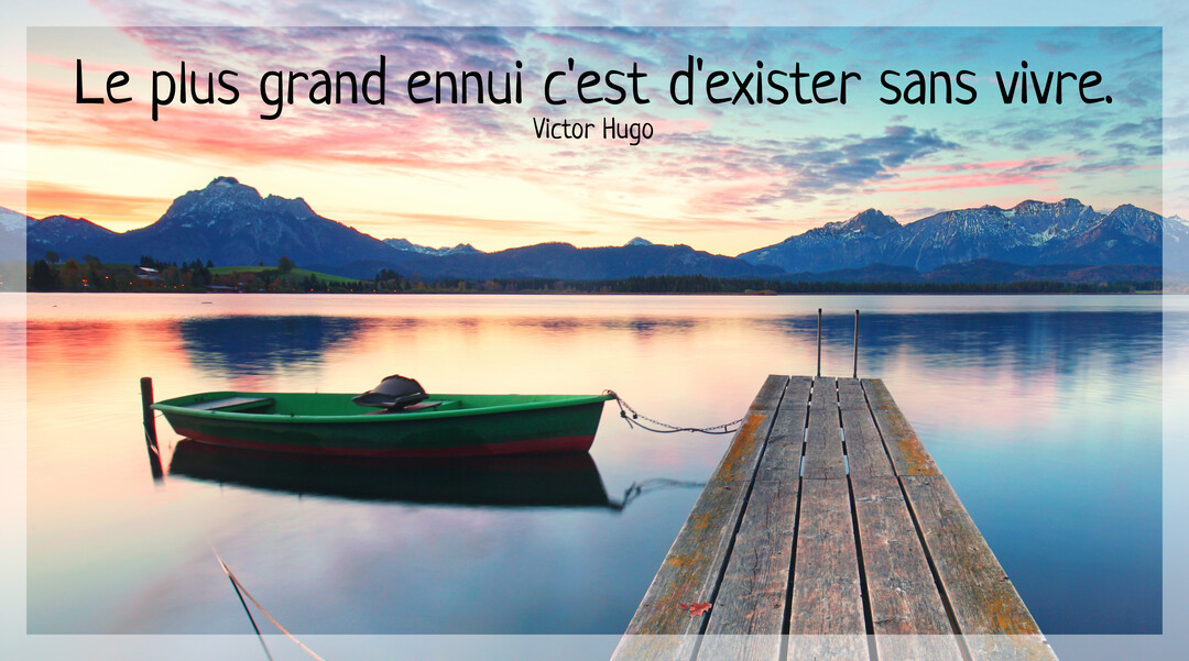 Un ponton en bois mène à un lac calme où une barque est amarrée, avec des montagnes en arrière-plan sous un ciel crépusculaire.