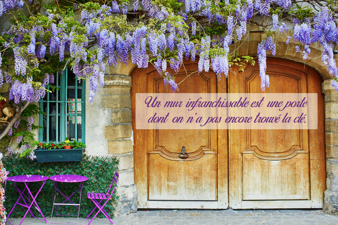 Une scène pittoresque montrant une porte en bois sous des cascades de glycine violette, avec une citation inspirante sur la persévérance superposée.