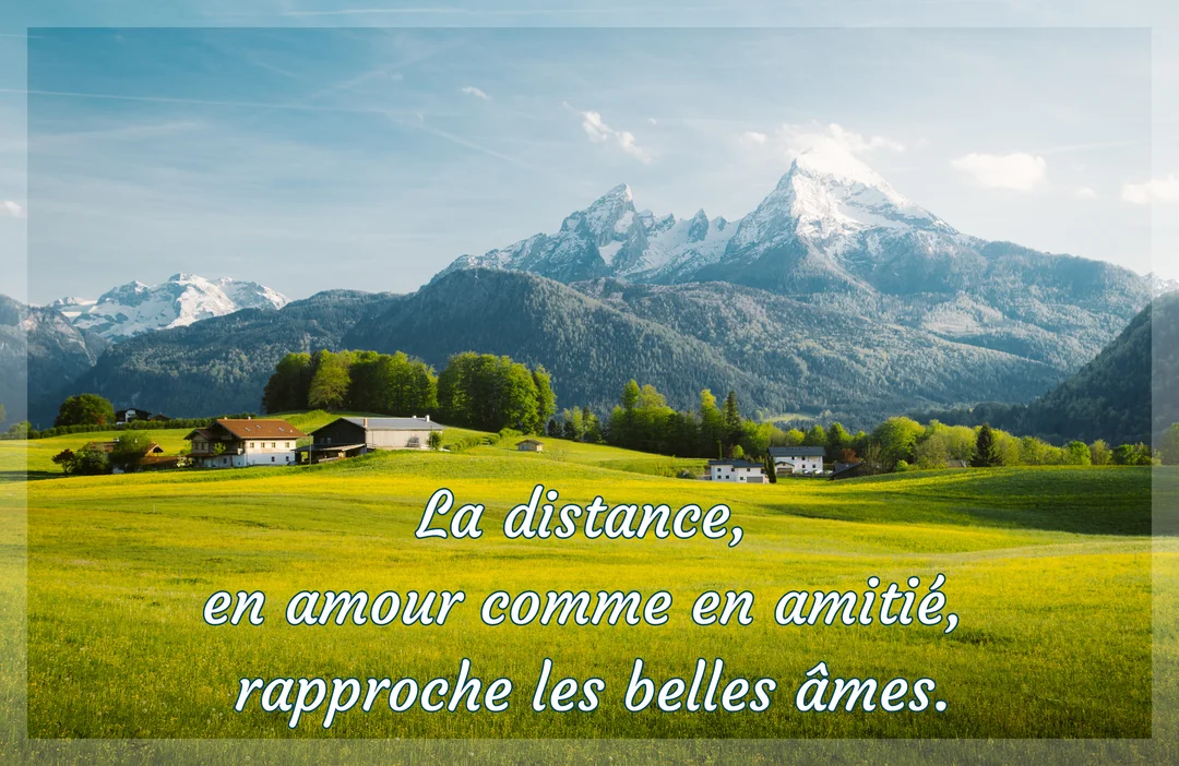 Une vue panoramique d'une vallée verdoyante parsemée de chalets, dominée par d'imposantes montagnes aux cimes enneigées sous un ciel bleu clair.