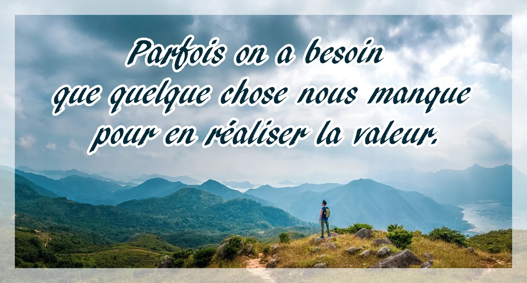 Un homme seul avec un sac à dos se tient au sommet d'une colline, observant une vaste étendue de montagnes verdoyantes et brumeuses.