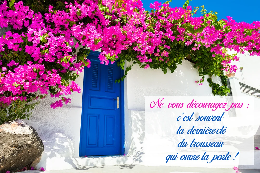 Photographie d'une façade blanche méditerranéenne avec une porte bleue, des fleurs de bougainvillier fuchsia luxuriantes et un ciel bleu en arrière-plan.
