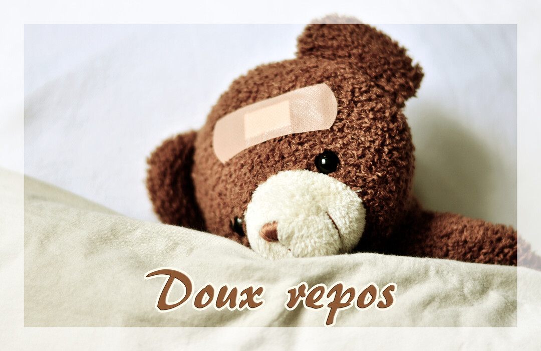 Un ours en peluche brun, avec un pansement sur le front, est couché sous une couverture, évoquant le repos et la convalescence.