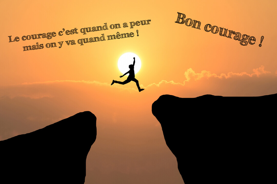 La silhouette d'une personne effectue un grand saut entre deux falaises, se détachant sur un ciel orangé au coucher du soleil.