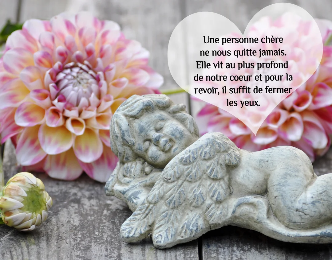 Une statuette d'ange en pierre dormant paisiblement est posée sur du bois à côté de dahlias rose et jaune, illustrant un texte de condoléances.
