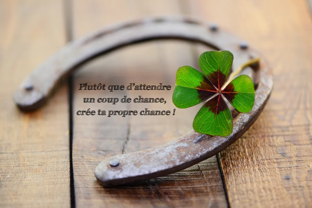 Un fer à cheval en métal rouillé et un trèfle à quatre feuilles sont posés sur des planches de bois rustiques.