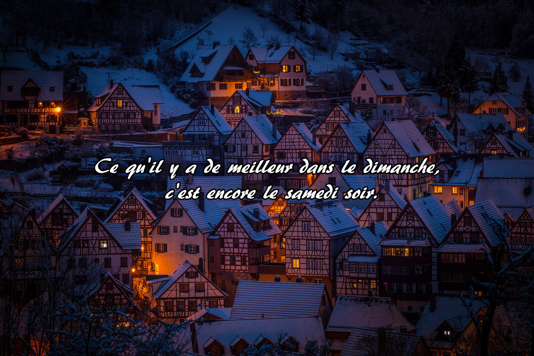 Vue nocturne d'un village pittoresque sous la neige, où des maisons à colombages aux fenêtres éclairées créent une ambiance chaleureuse et hivernale.