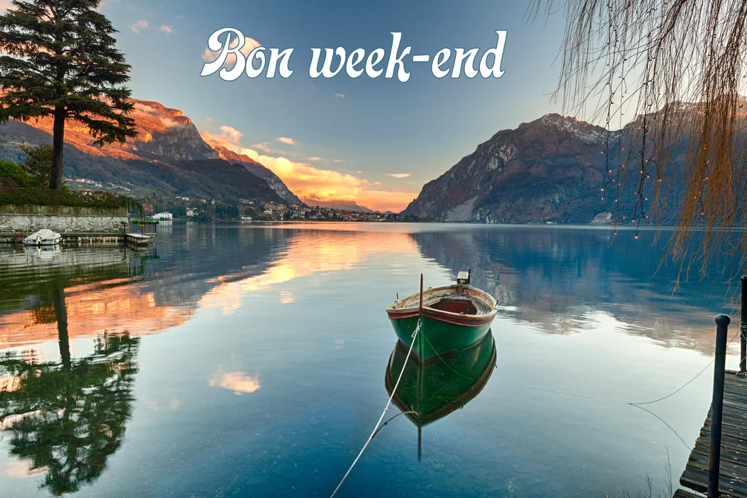 Une barque verte flotte sur un lac calme au crépuscule, reflétant les montagnes et un ciel coloré, avec le texte "Bon week-end".