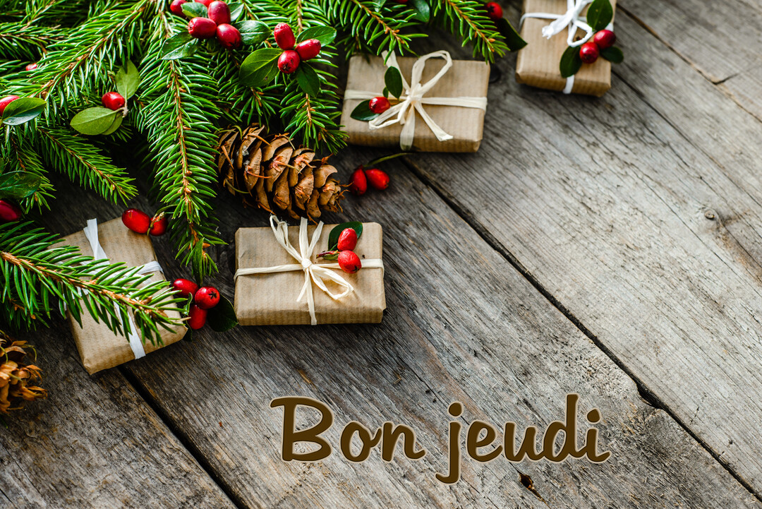 Une composition festive vue de dessus avec des cadeaux, des branches de sapin et des baies rouges posés sur des planches de bois vieillies.