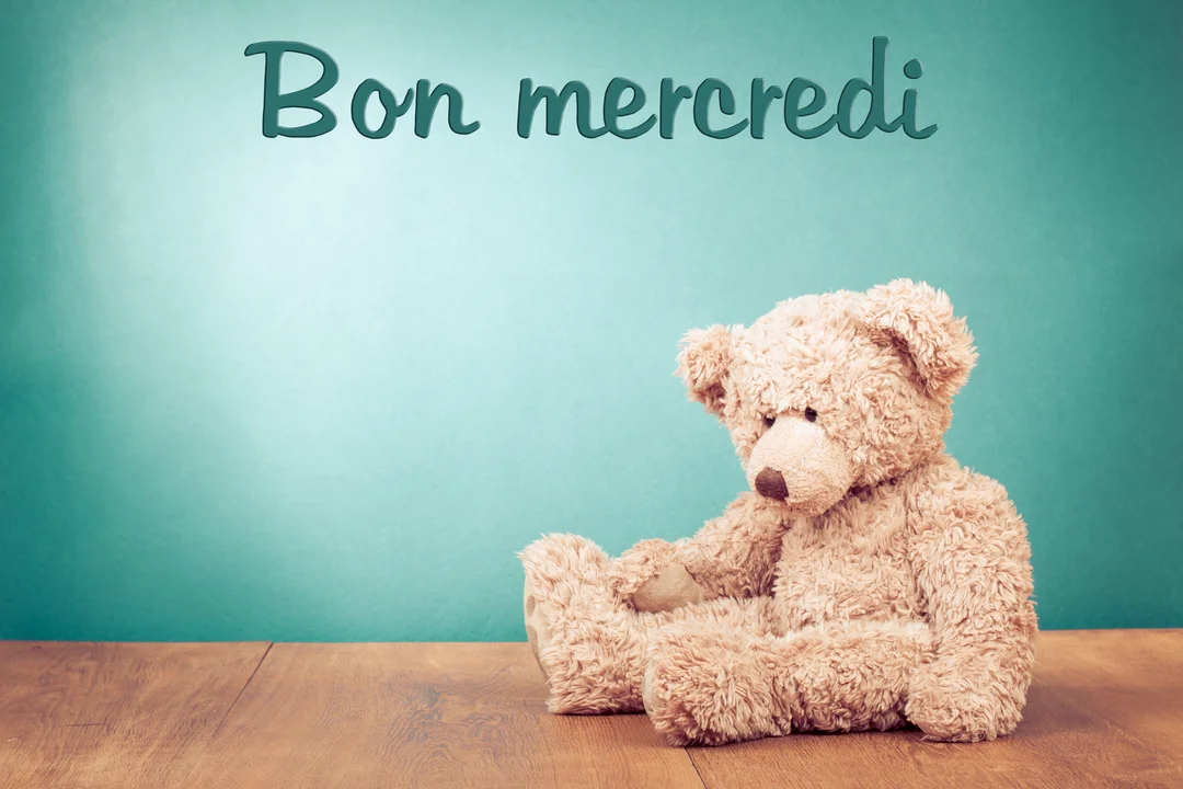 Un ours en peluche beige est assis seul sur un plancher en bois, avec le texte 'Bon mercredi' inscrit sur un fond turquoise.