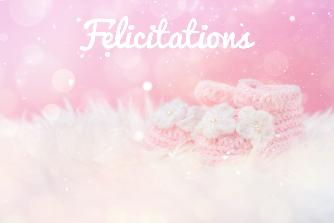 Une paire de chaussons de bébé en tricot rose avec des fleurs blanches repose sur une fourrure blanche, sur un fond rose lumineux et scintillant.