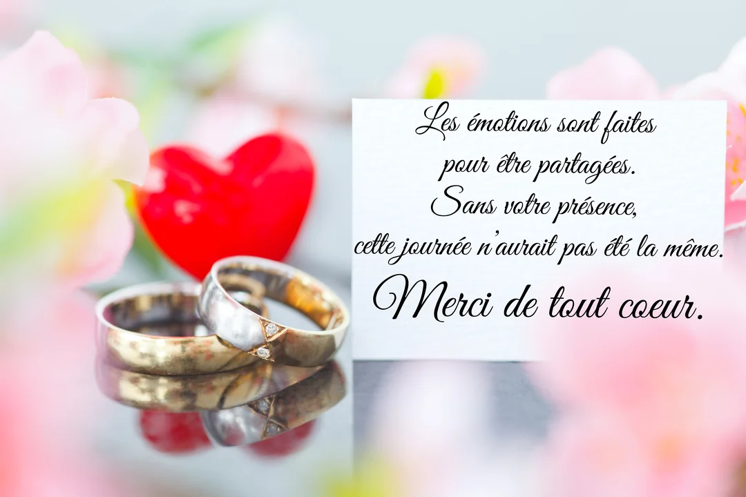 Deux alliances dorées et argentées se reflètent devant un cœur rouge et des fleurs roses, accompagnées d'un message de remerciement manuscrit.