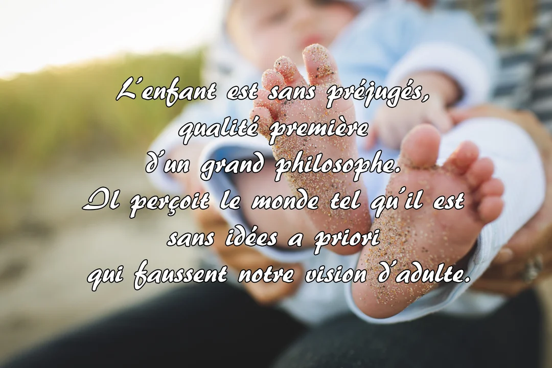 Gros plan sur les pieds d'un bébé couverts de sable fin, délicatement tenus dans les mains d'un parent, sur un fond flou.