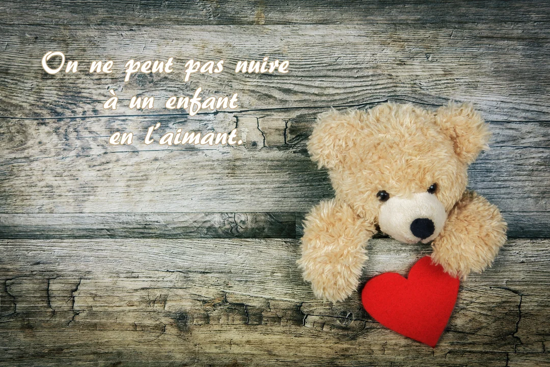Un adorable ours en peluche beige est allongé sur un fond en bois rustique, ses pattes posées sur un cœur en tissu rouge.