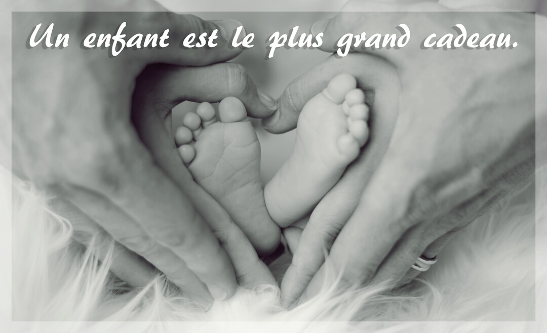 Photographie en noir et blanc de mains d'adulte formant un cœur autour des deux petits pieds d'un nouveau-né sur une surface douce et duveteuse.