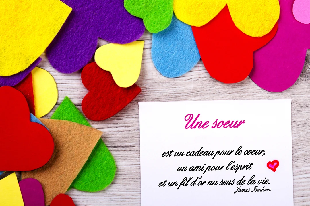 Sur un fond de bois clair, une carte blanche porte une citation sur les soeurs, entourée de coeurs multicolores en feutrine.