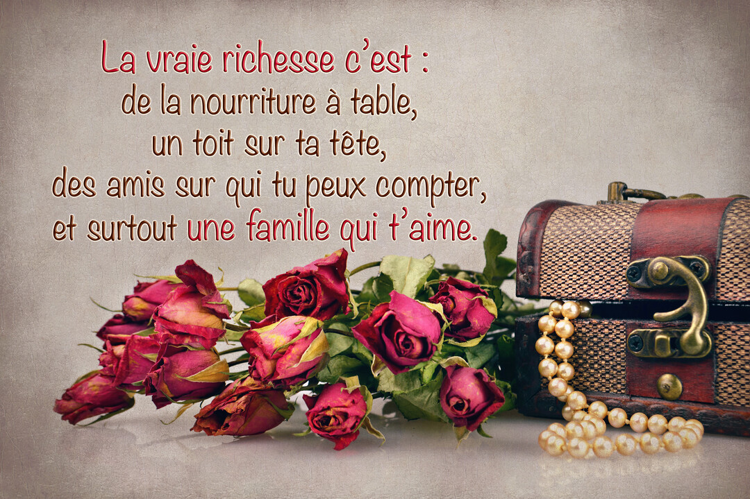Une composition de style vintage avec un bouquet de roses rouges séchées à côté d'un coffre en bois ouvert révélant un collier de perles.