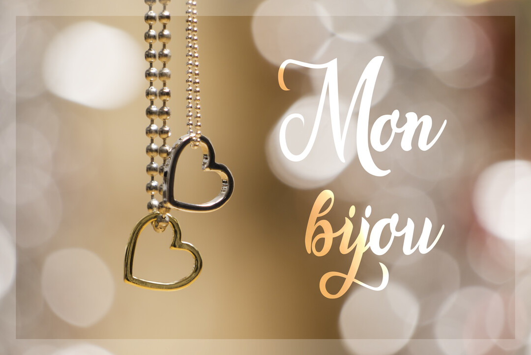 Deux pendentifs en forme de cœur, or et argent, suspendus à leurs chaînes sur un fond doré avec un effet bokeh lumineux.