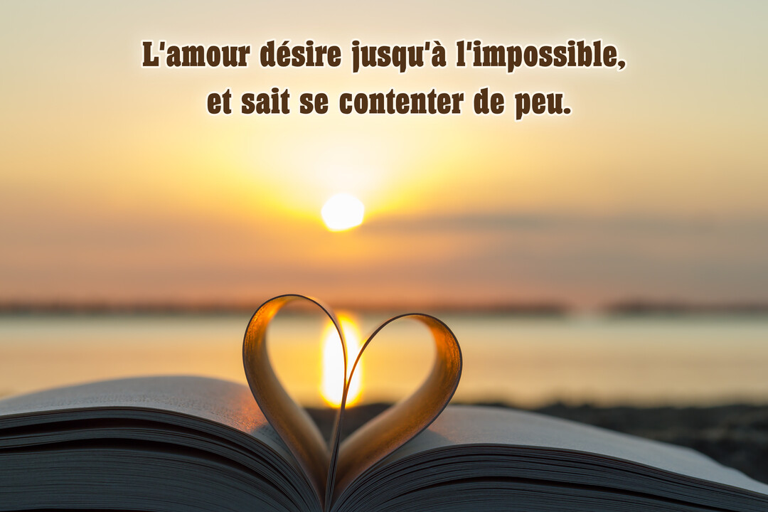 Un livre ouvert au premier plan, dont deux pages sont pliées pour former un cœur, avec en arrière-plan un magnifique coucher de soleil sur l'océan.