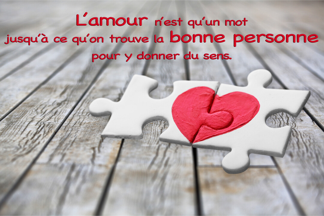 Deux pièces de puzzle blanches assemblées sur des lattes de bois forment un cœur rouge, illustrant une citation d'amour écrite au-dessus.