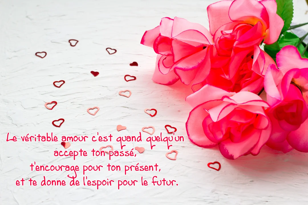 Sur un fond blanc texturé, des roses artificielles roses accompagnent une citation d'amour et des confettis en forme de cœurs rouges et roses.